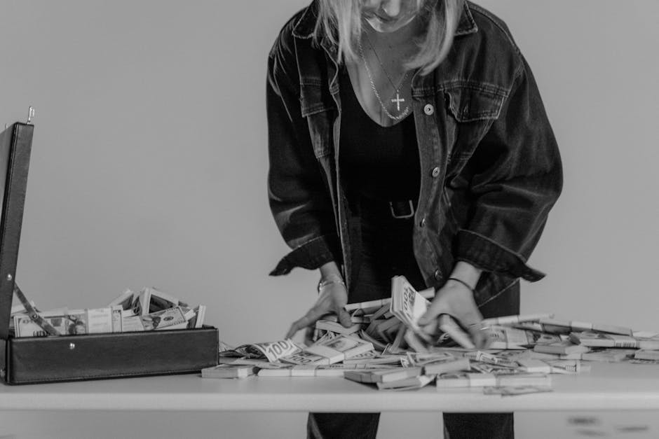 Black and white image depicting a woman handling stacks of US dollar bills with a briefcase.