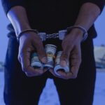 Close-up of handcuffed hands holding rolled cash, suggesting crime or arrest.